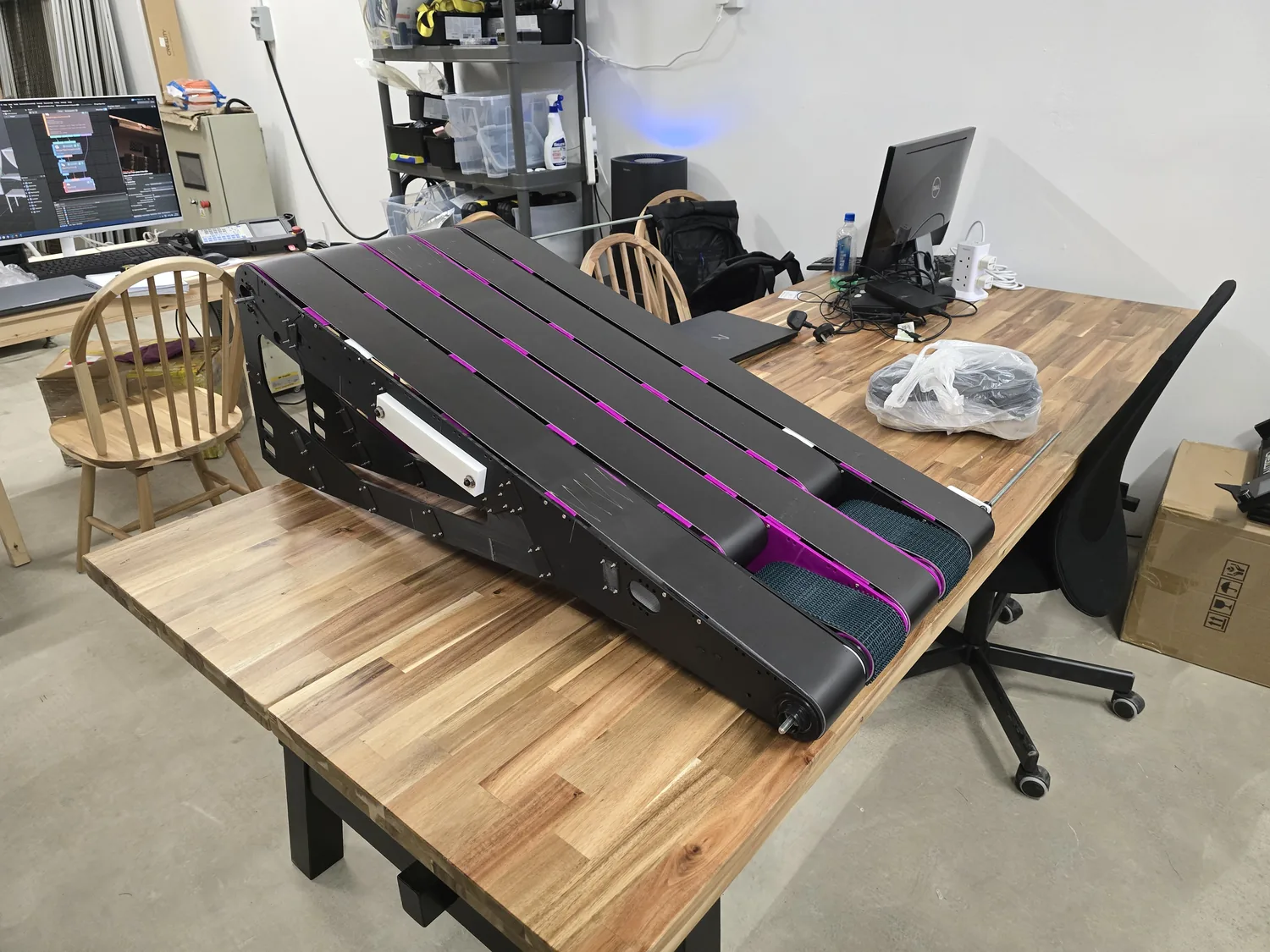 Der fertig montierte Fork Lifter auf dem Tisch: schwarze Konstruktion mit sieben magentafarbenen Riemen, identisch zum CAD-Entwurf.
